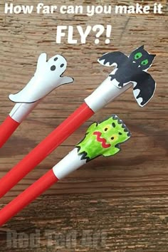 two plastic toothbrushes with halloween decorations on them sitting on a wooden table next to each other