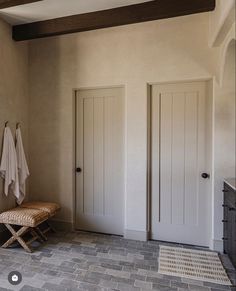 a bathroom with two doors and a bench in front of the door is tiled floor