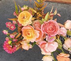 a bouquet of flowers sitting on the ground next to a person's feet and shoes