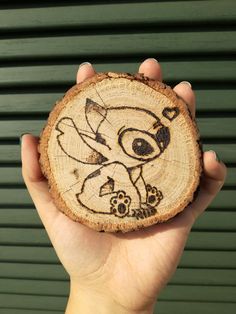 a hand holding a piece of wood with an image of a cartoon character on it