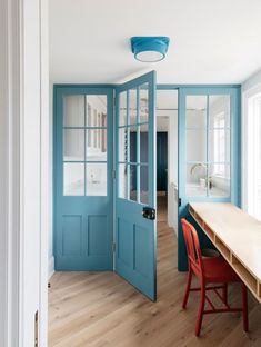 a dining room with blue doors and wooden floors