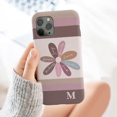 a person holding up a phone case with a flower on the front and initials on the back