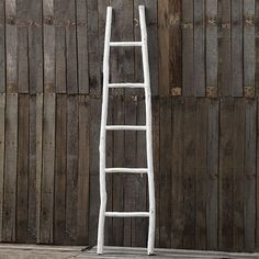 a white ladder leaning against a wooden wall