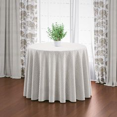 a potted plant sitting on top of a table next to a curtained window