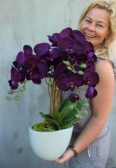 a woman holding a potted plant with purple flowers