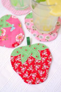 an apple shaped coaster sitting on top of a table next to a glass filled with lemonade