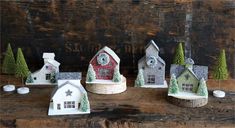 three small houses with trees and snow on them are sitting on a wooden table next to each other