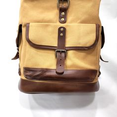 18oz Cotton Canvas with a commercial grade water repellent. Cinch top with flap. Full Grain Leather Trim Matte Gold Metal Tooth Zipper Size: 21" x 13" x 8" Modern Brown Bags For Outdoor, Modern Brown Outdoor Bag, Functional Brown Bag With Leather Backing, Canvas Tote Bags With Leather Backing, Brown Waxed Canvas Standard Backpack, Classic Beige Rectangular Backpack, Waxed Canvas Backpack With Large Capacity, Waxed Canvas Large Capacity Backpack, Beige Travel Bag With Waxed Finish