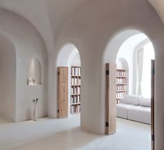 an arched room with bookshelves and couches in the corner, all white