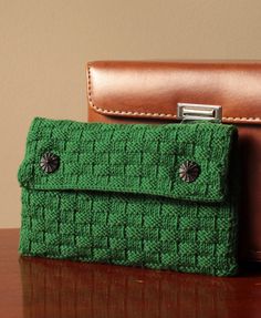 two green purses sitting on top of a wooden table