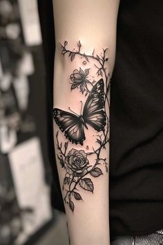 a woman's arm with a butterfly and roses tattoo on it