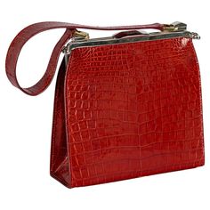 Crafted by Dotti in Roma, Italy during the early 21st Century, this handbag boasts red crocodile leather adorning both its exterior and handle. Gleaming gold and palladium plated hardware, from its clasp to the clam shell opening system, accentuates its elegance. The interior, marked with "DOTTI Via Belsiana 26, Roma," comprises two petite compartments alongside the primary section, all fashioned from a soft red leather. The two inner compartments have an added, quirky, multicolour "$" pattern f Luxury Red Crocodile Pattern Bag, Cheap Red Crocodile Pattern Bag, Roma Italy, Soft Red, Clam Shell, Crocodile Leather, Pattern Fabric, Metal Crafts, Gold Enamel