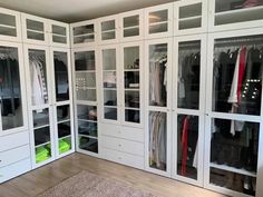 a walk in closet filled with lots of white cupboards and clothes hanging on hooks