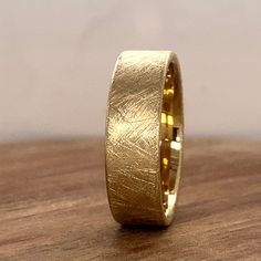 a yellow gold wedding band on top of a wooden table