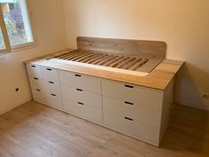 an empty bedroom with white drawers and a bed in the corner next to a window