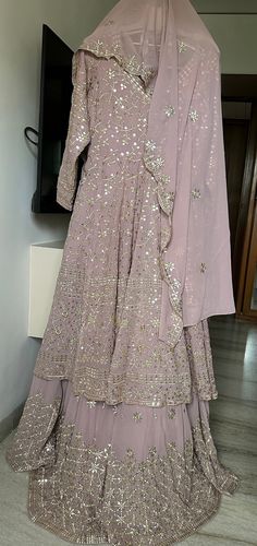 A beautiful soft onion, pink colour Lehenga with full Ghera /flare  and cancan to give complete wedding  wear look. The colour of this is so well, suitable for bride, bridesmaids mother of the bride or everyone. The work is done in dull Gold and mirror work, which gives it a perfect soft bling and not too shiny to make it very alluring and elite. The top of the Lehenga is a full Gera Anarkali, which has worked all over front and back and Tailor to fit size large US size 12 The dupatta also has border on all four sites and butties all over. One can also wear this outfit in another form using the  Anarkali top with a simple pants and dupatta that making it a Anarkali suit.  So, when you buy this Lehenga, it is like buying two exclusive wedding wear dresses. Onion Colour Suit, Wedding Choli For Festivals In Maxi Length, Bollywood Style Maxi Length Wedding Choli, Maxi Length Choli For Wedding And Festivals, Maxi Length Wedding Choli For Festivals, Pink Maxi Gown With Sheer Dupatta, Wedding Anarkali Floor-length Sharara, Wedding Anarkali Style Floor-length Sharara, Anarkali Style Floor-length Wedding Sharara