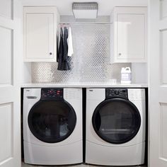 a washer and dryer in a small room with white cabinets on the wall