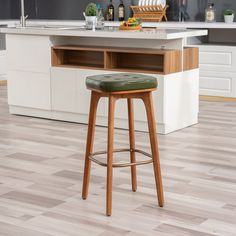 a bar stool with a green leather seat in front of a kitchen island and counter