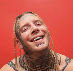 a man with dreadlocks and tattoos on his face is smiling at the camera