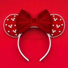 a red minnie mouse ears headband with pearls on it's side and a bow at the top