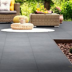 an outdoor patio with wicker furniture and plants in the backgroung area