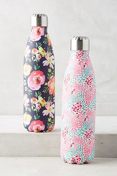 two colorful water bottles sitting next to each other on top of a white countertop