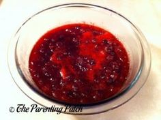 a glass bowl filled with cranberry sauce on top of a table