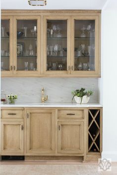 a kitchen with wooden cabinets and white counter tops in front of a wine glass cabinet