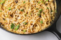 a skillet filled with pasta and parmesan cheese on top of a table