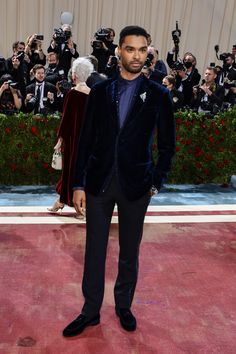 a man in a blue velvet suit standing on a red carpet with cameras around him