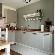 a kitchen with grey cabinets and white appliances in the center, along with a wooden dining table