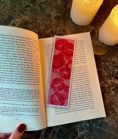 an open book sitting on top of a table next to candles