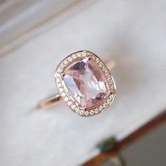 an engagement ring with a large pink stone surrounded by small white diamonds on the side