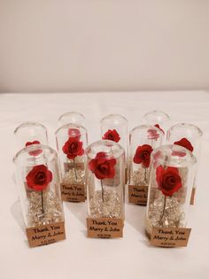 small glass jars with red roses in them