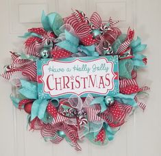 a christmas wreath on the front door with red, white and blue ribbons around it