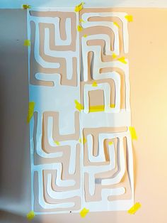 a piece of paper cut out to look like a maze with yellow tape on it