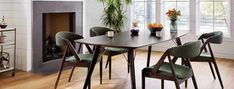 a dining room table with green chairs and a fire place in the corner next to it