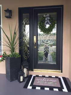 a welcome mat sits on the front porch next to a potted plant and candle