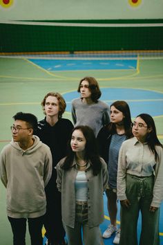 a group of young people standing on top of a tennis court next to each other