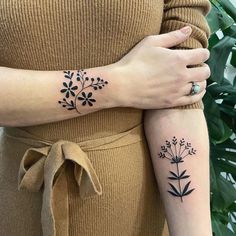 two women with matching tattoos holding each other's arms, both showing the same tattoo designs