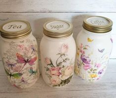 three jars with flowers and butterflies painted on them