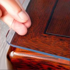 a person holding a knife in their right hand on top of a wooden table next to a mirror