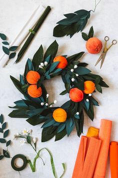 an orange wreath surrounded by scissors, flowers and other crafting supplies on a white surface