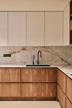 a kitchen with marble counter tops and wooden cabinetry, along with a sink that has a black faucet on it