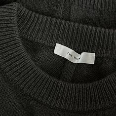 the row black sweater with white tag on it's chest and collar, close up