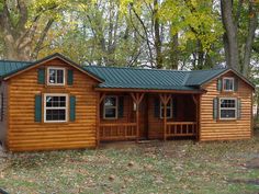 a small log cabin in the woods with green shutters on the front and side windows