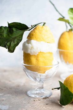 two lemons with ice cream and leaves in small glass bowls on a countertop