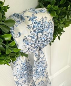 a blue and white scarf hanging on a door handle next to a potted plant