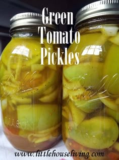 two jars filled with pickles sitting on top of a table