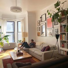 a man sitting on top of a couch in a living room next to a window